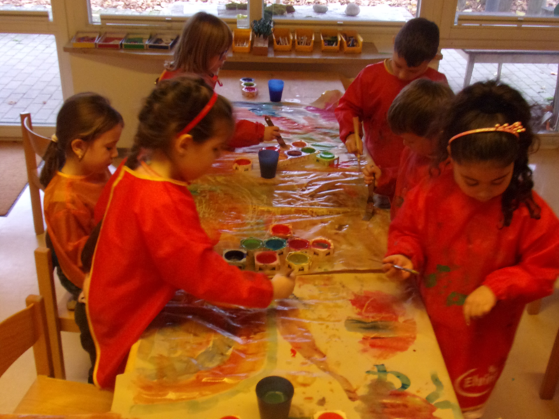 Ein großer Tisch an dem viele Kinder sitzen und malen.